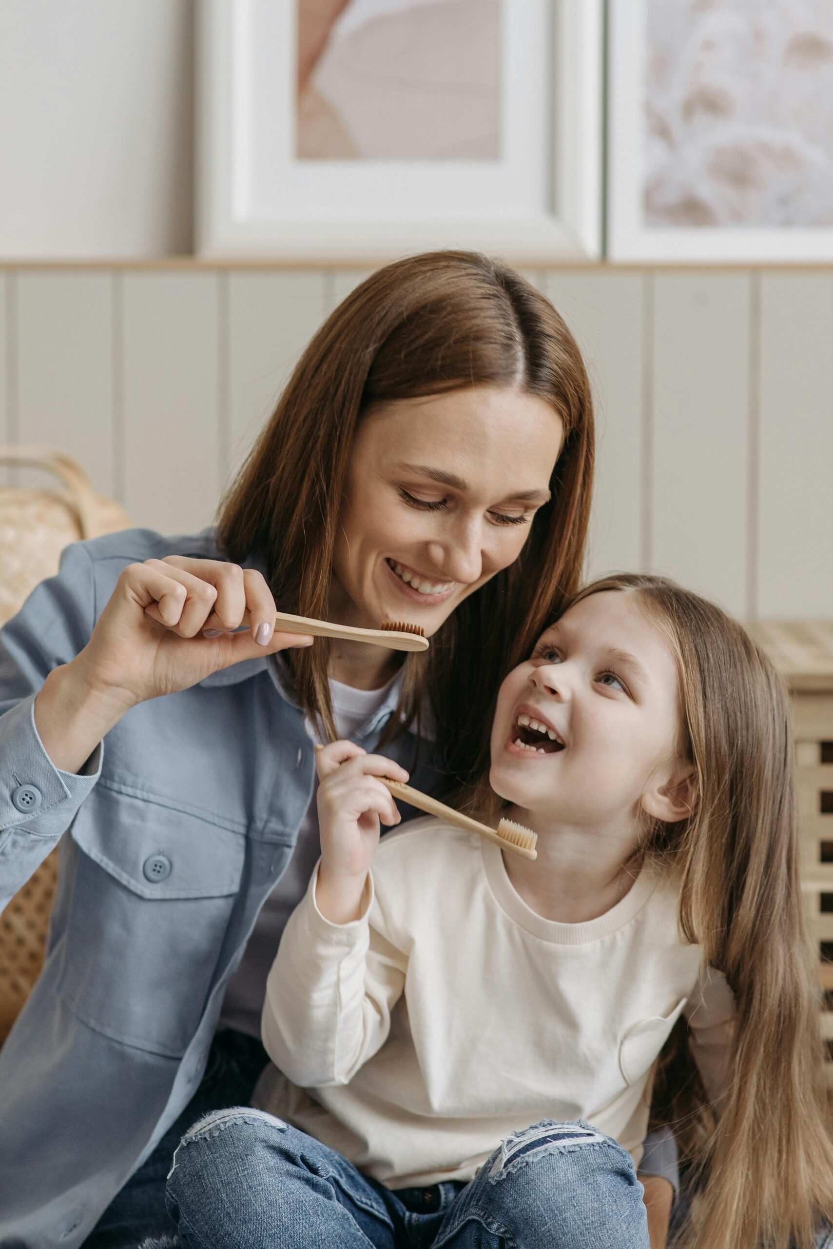 A mother and daughter enjoying quality time while brushing their teeth together indoors.